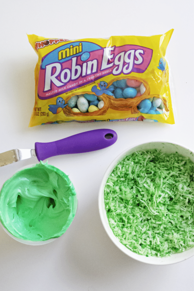 Adding green food coloring to coconut shreds, two separate bowls one green frosting, one green coconut flakes