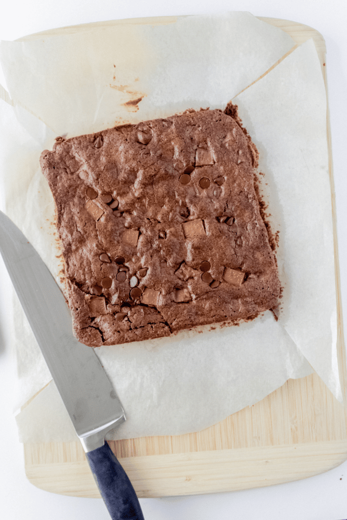 Cutting into double chunk brownies on cutting board with sharp knife