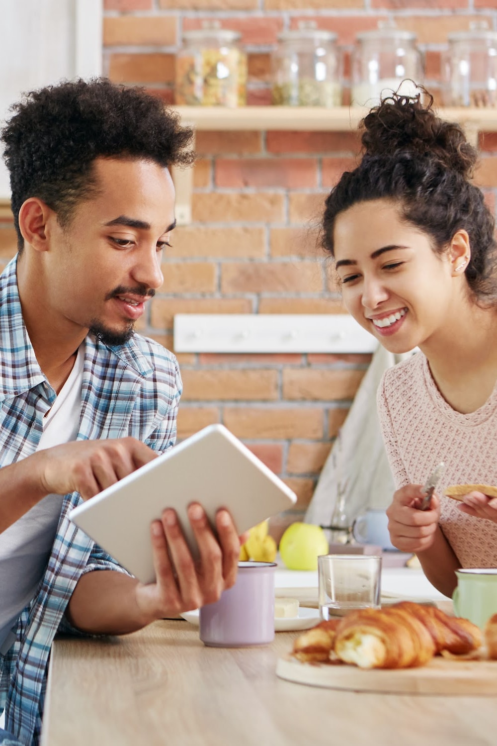 happy couple shopping online together while eating breakfast at table