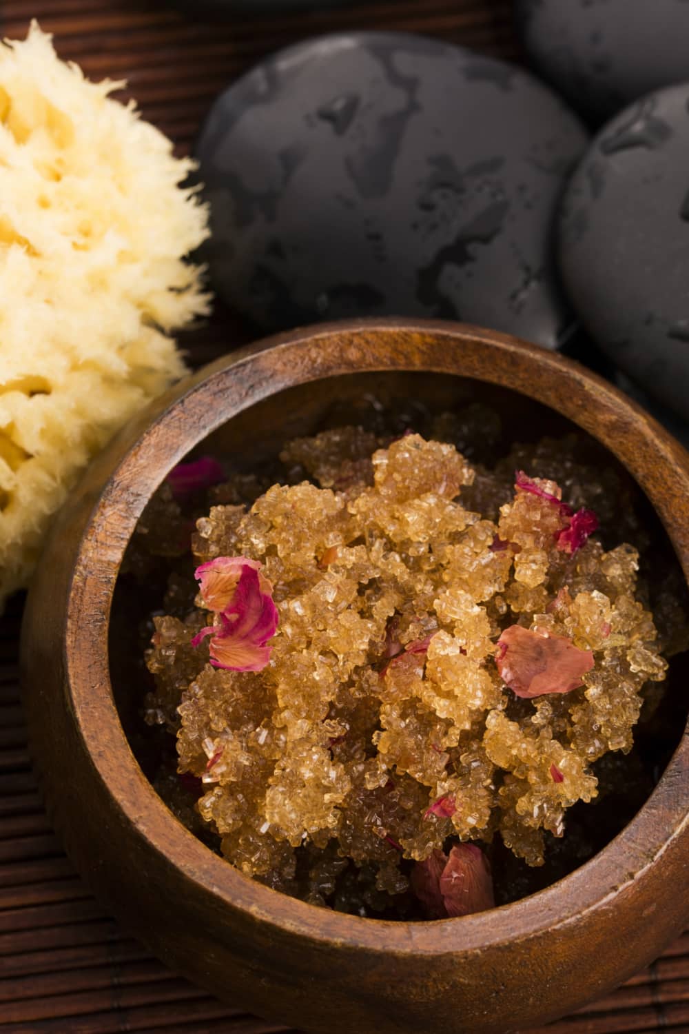 brown sugar facial scrub in brown wooden bowl next to loofah sponge