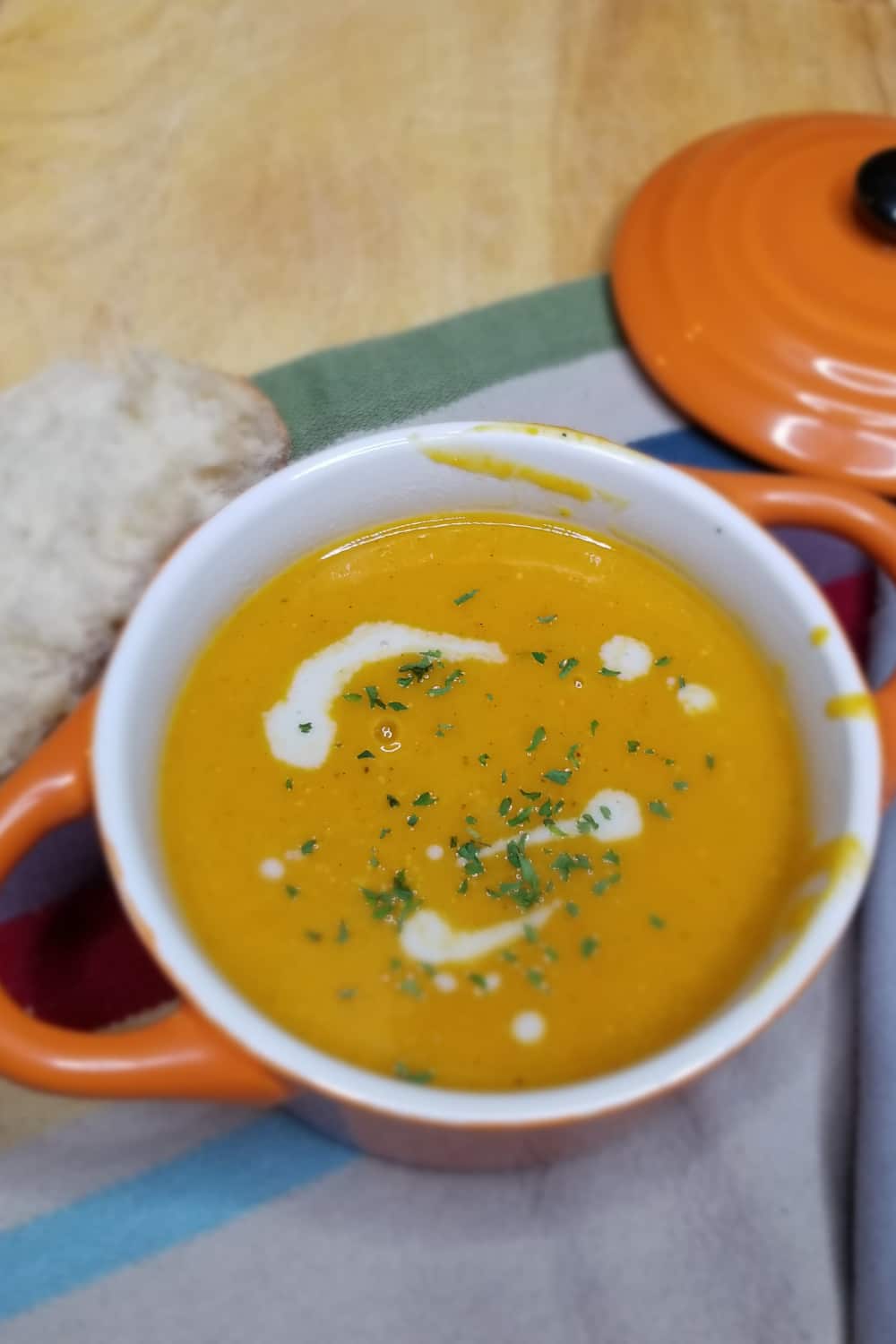 butternut squash soup in orange bowl on table