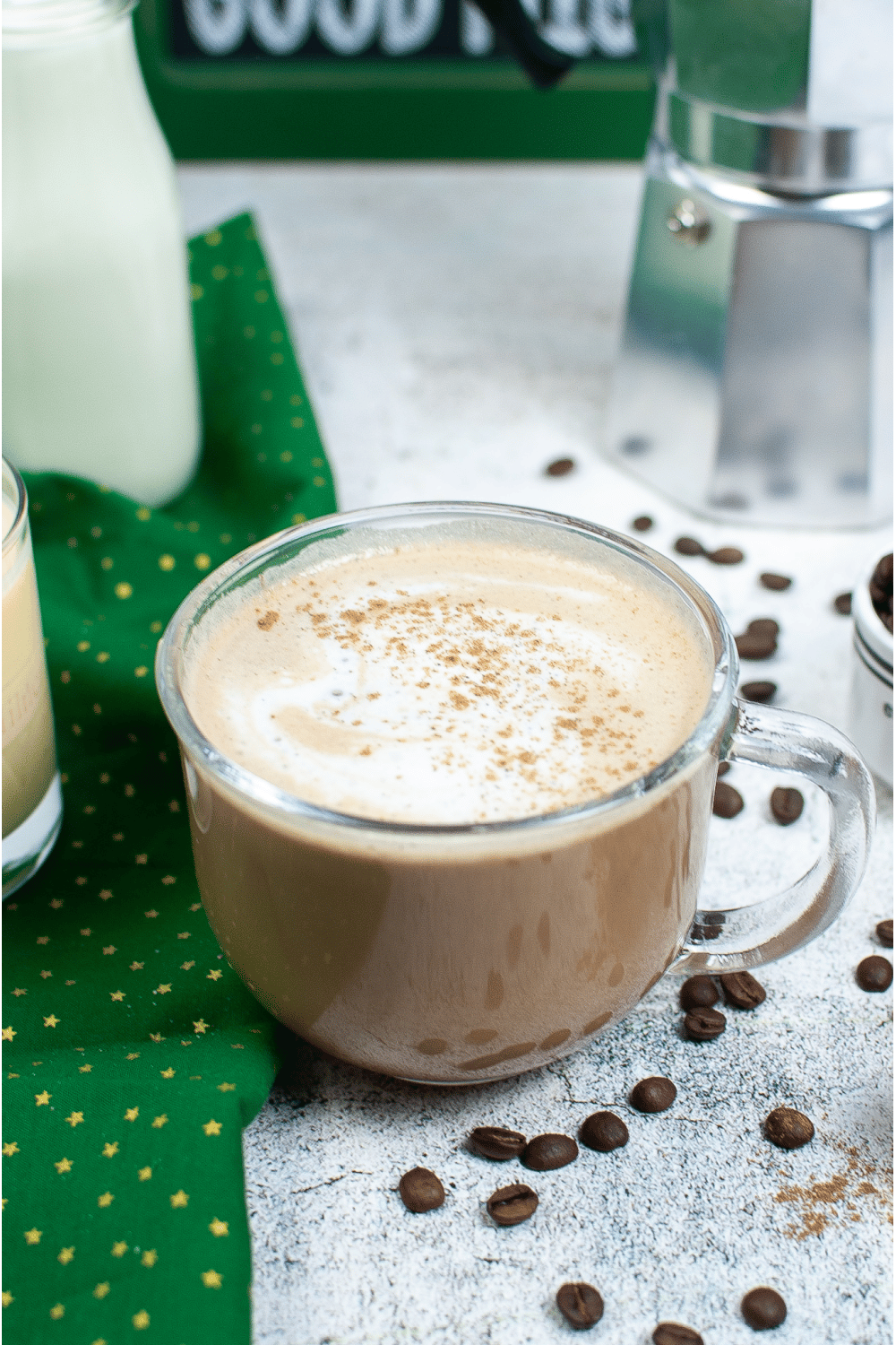 Starbucks copycat eggnog latte in glass coffee mug with scattered coffee beans on white background