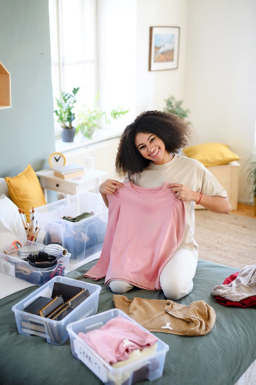 a woman sorting through clothes on the floor declutting home