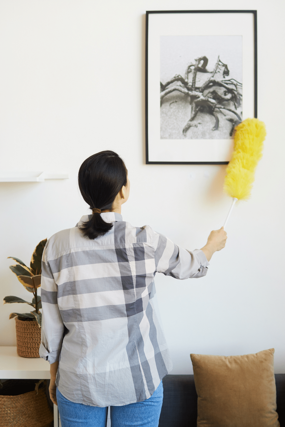 Woman Dusting frame in living room